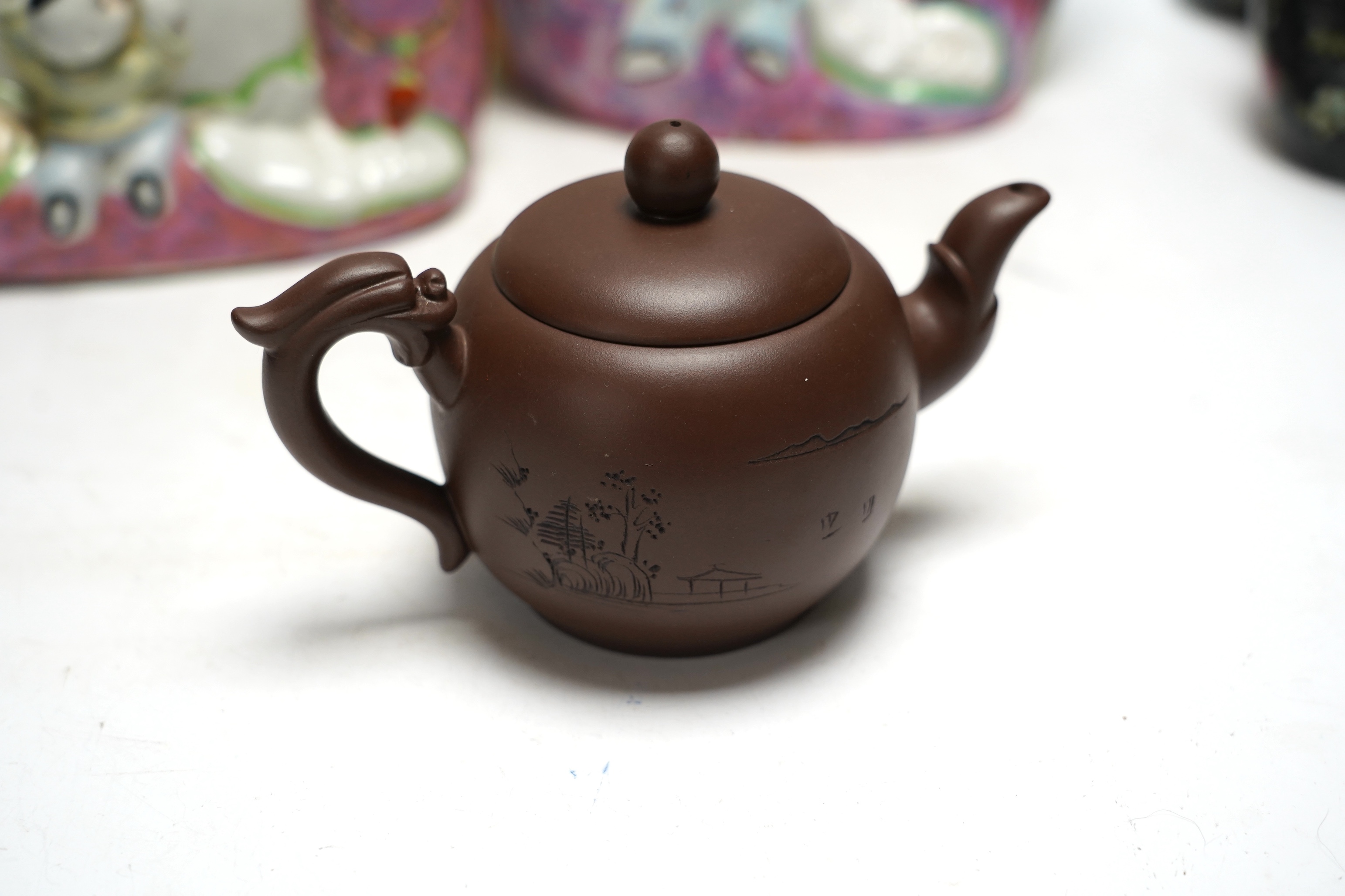 Two figural Chinese pillows, two famille rose Budai groups and three yixing teapots, tallest 25cm